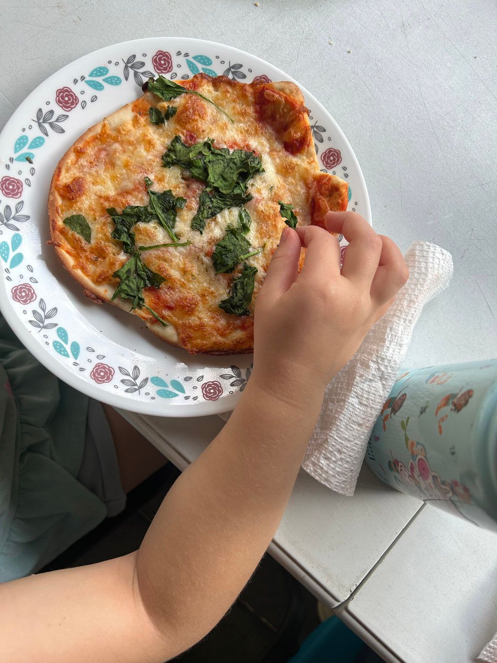 child’s hand reaching for pizza