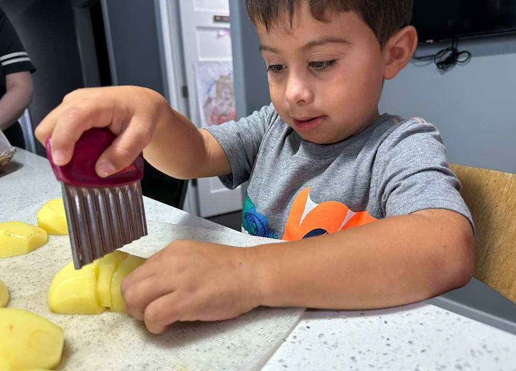 child chops potatoes with a child-sized cutter