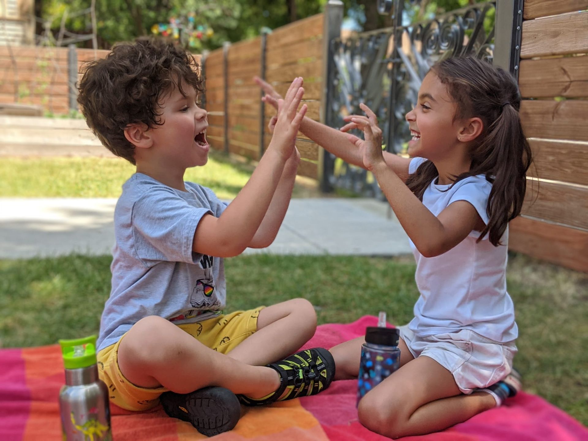 Two young seated children facing each other playing a finger game.