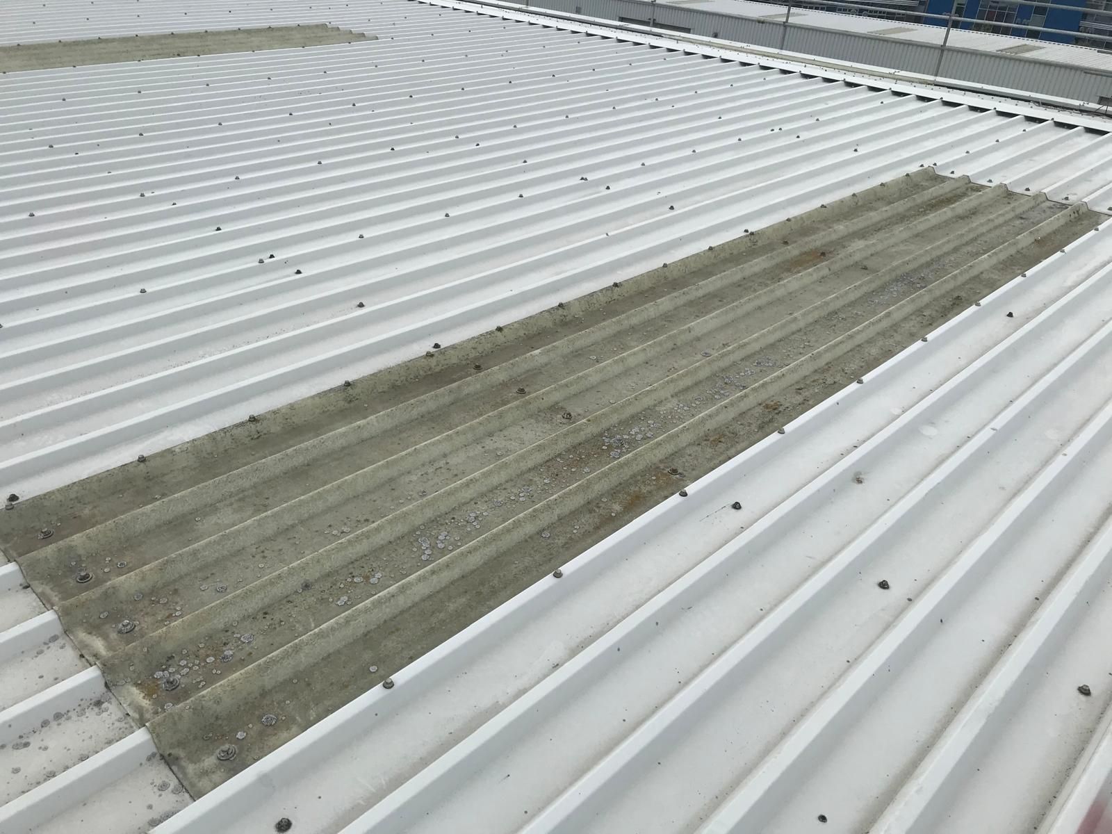 White corrugated metal roof with two rectangular patches of gray debris.