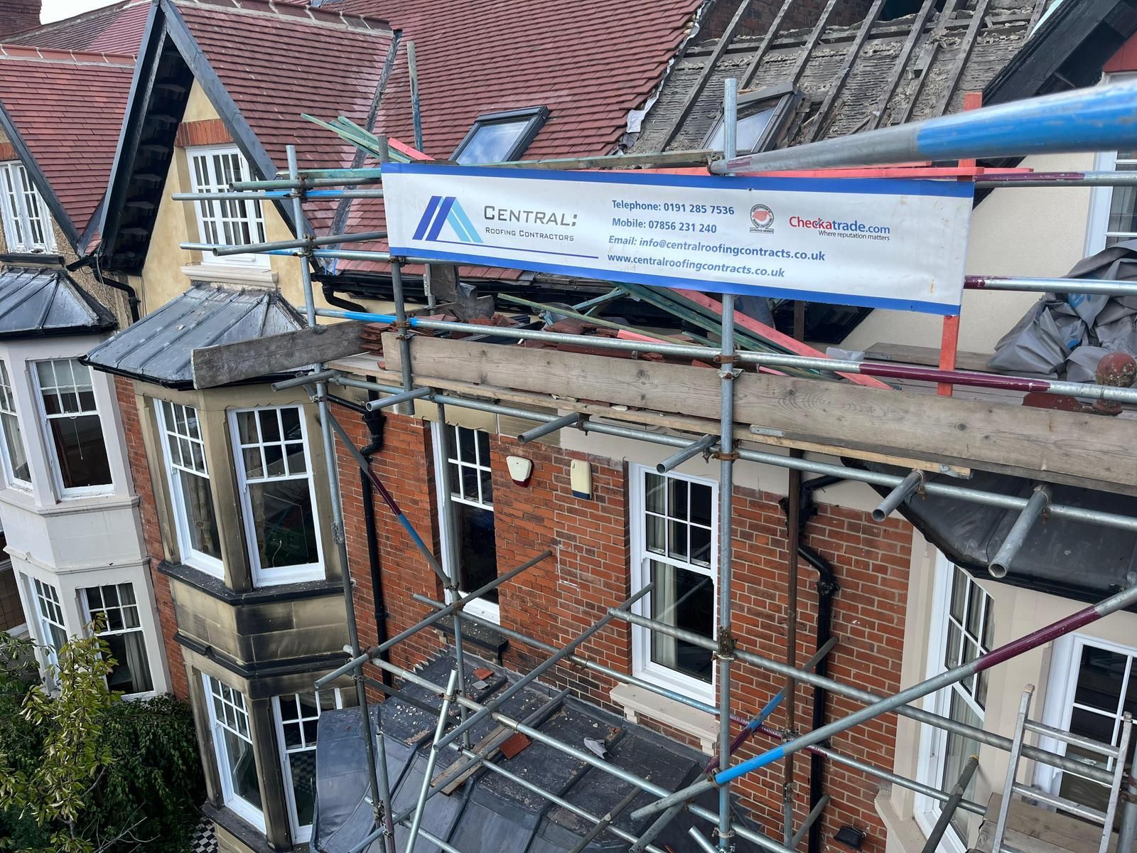 Roofer using a torch to heat and seal a roll of roofing material on a flat roof.