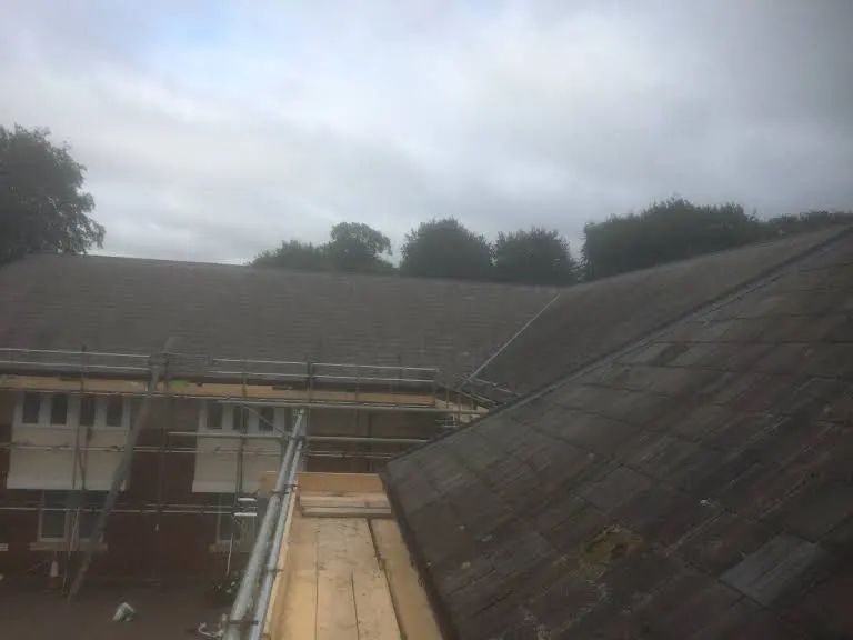 A rooftop with scaffolding, cloudy sky in background; building construction.