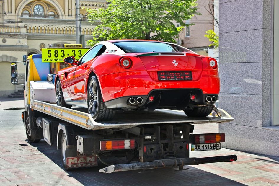 A red ferrari is being towed by a tow truck.
