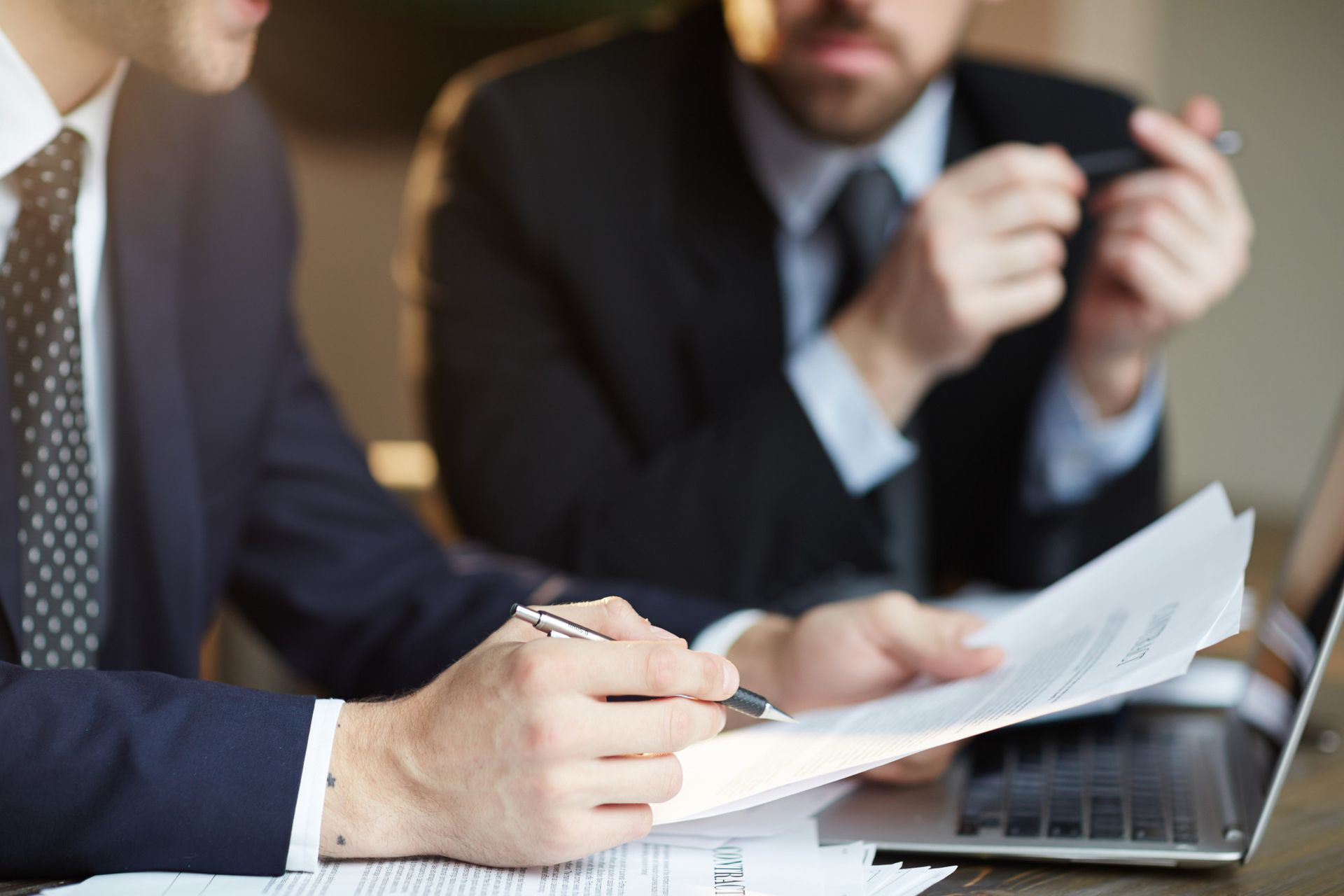 Business meeting with two people reviewing documents beside a laptop.