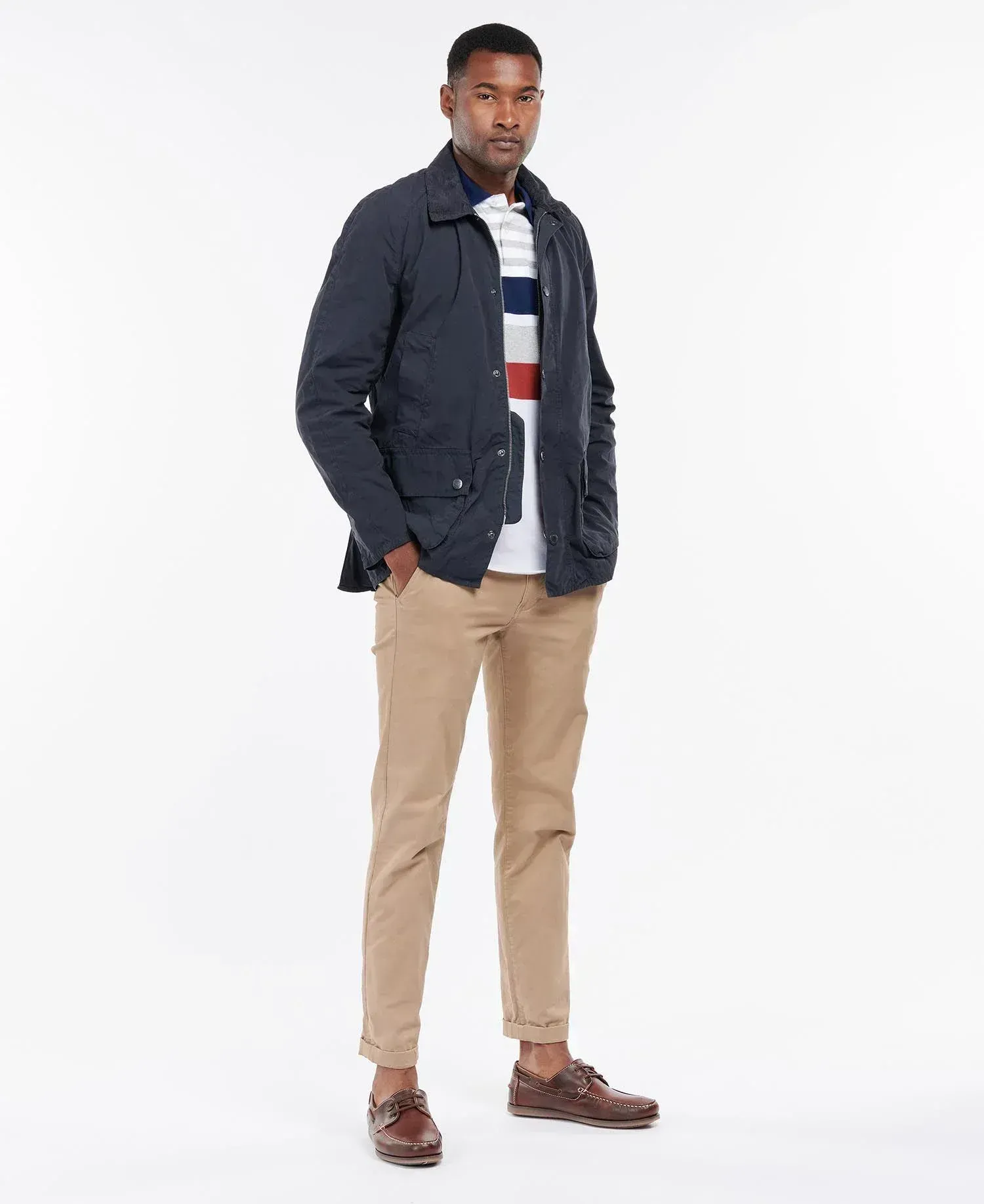 Un uomo che indossa una giacca blu e pantaloni color cachi è in piedi su uno sfondo bianco.