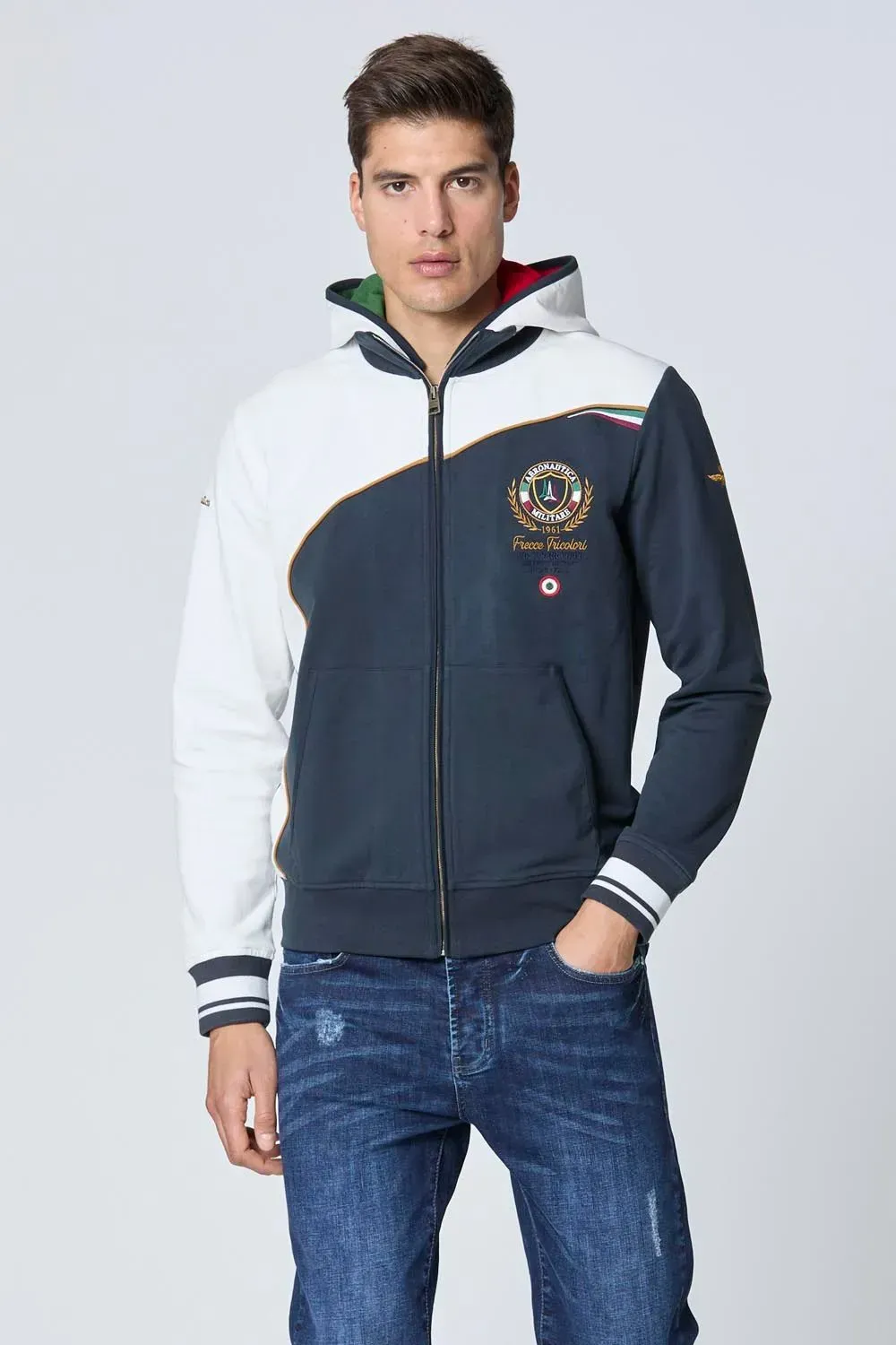 Un uomo che indossa una felpa con cappuccio blu e bianca e jeans