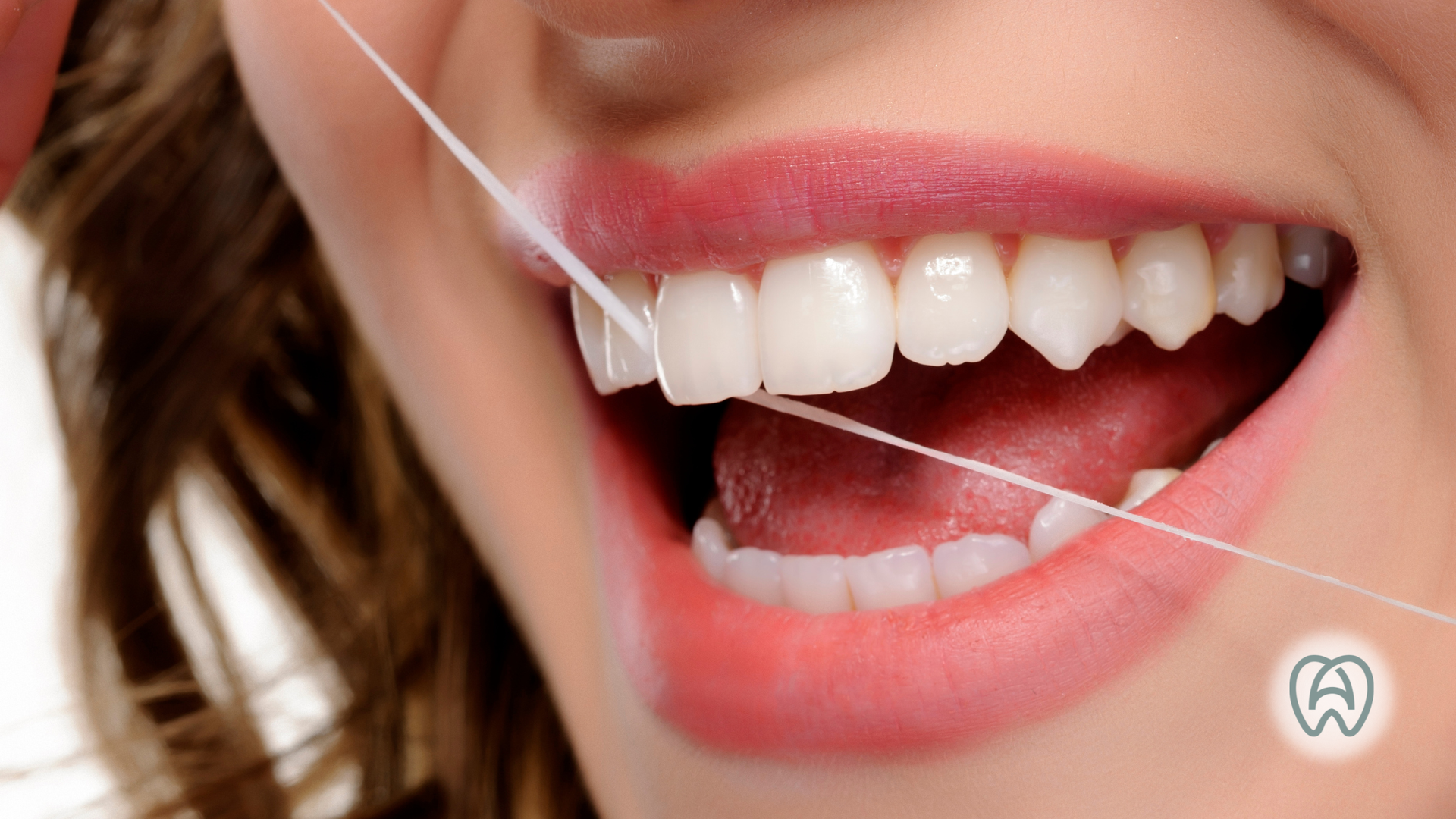 Close-up of a smiling mouth with teeth being flossed against a pink lip background
