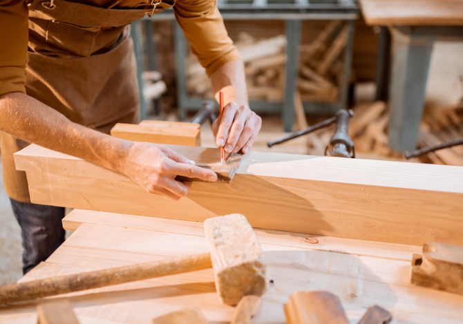 A man is working on a piece of wood in a workshop.