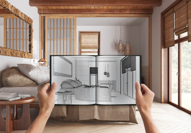 A person is holding a book with a drawing of a bedroom in it.