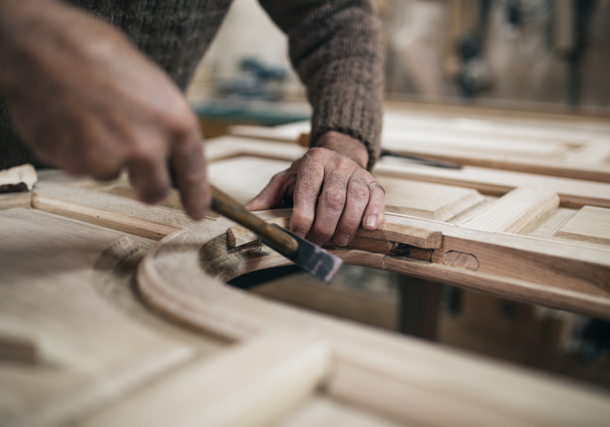 A man is working on a piece of wood with a hammer.