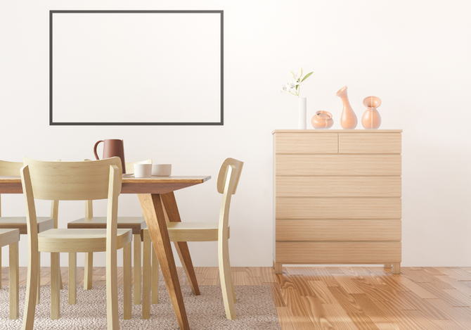 A dining room with a table and chairs and a picture frame on the wall.