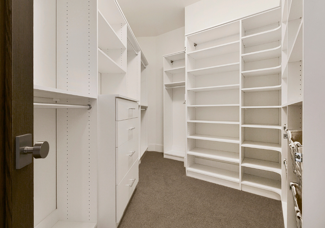 A walk in closet with lots of shelves and drawers.