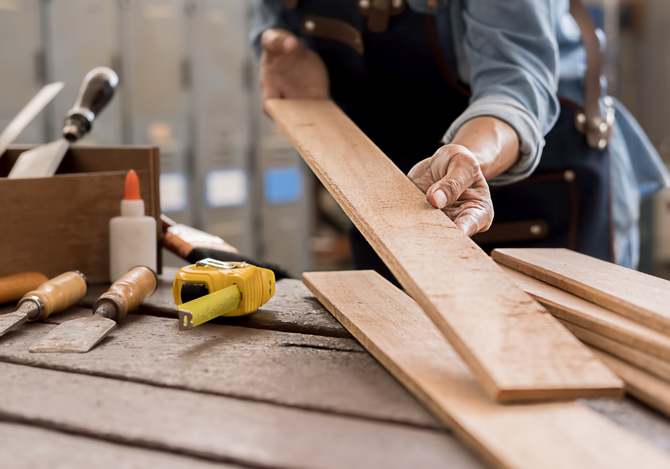 A person is measuring a piece of wood on a table.