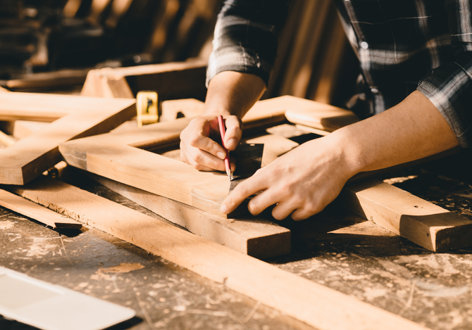 A person is measuring a piece of wood with a ruler.