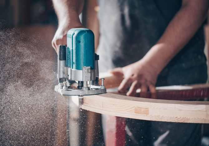 A man is using a router to cut a piece of wood.