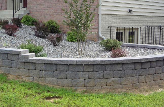 A stone wall surrounds a garden in front of a house.