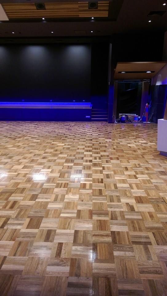 A large empty room with a wooden floor and a stage.