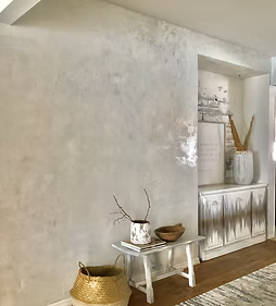 Neutral-toned living room with rustic white cabinet, small table, and woven baskets on wood floor
