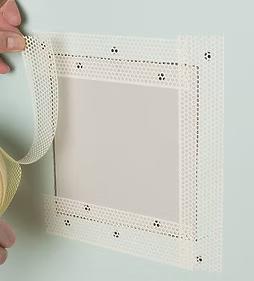 Hands holding a white perforated adhesive frame with a blank center panel