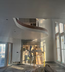 Interior under construction with ladders, exposed walls, and a curved balcony opening above windows