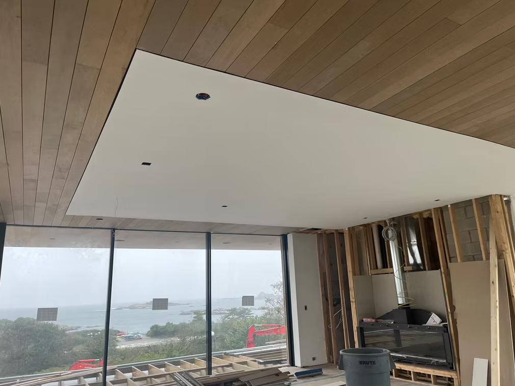 Modern room with wood ceiling, large window view of water, and a built-in bar area