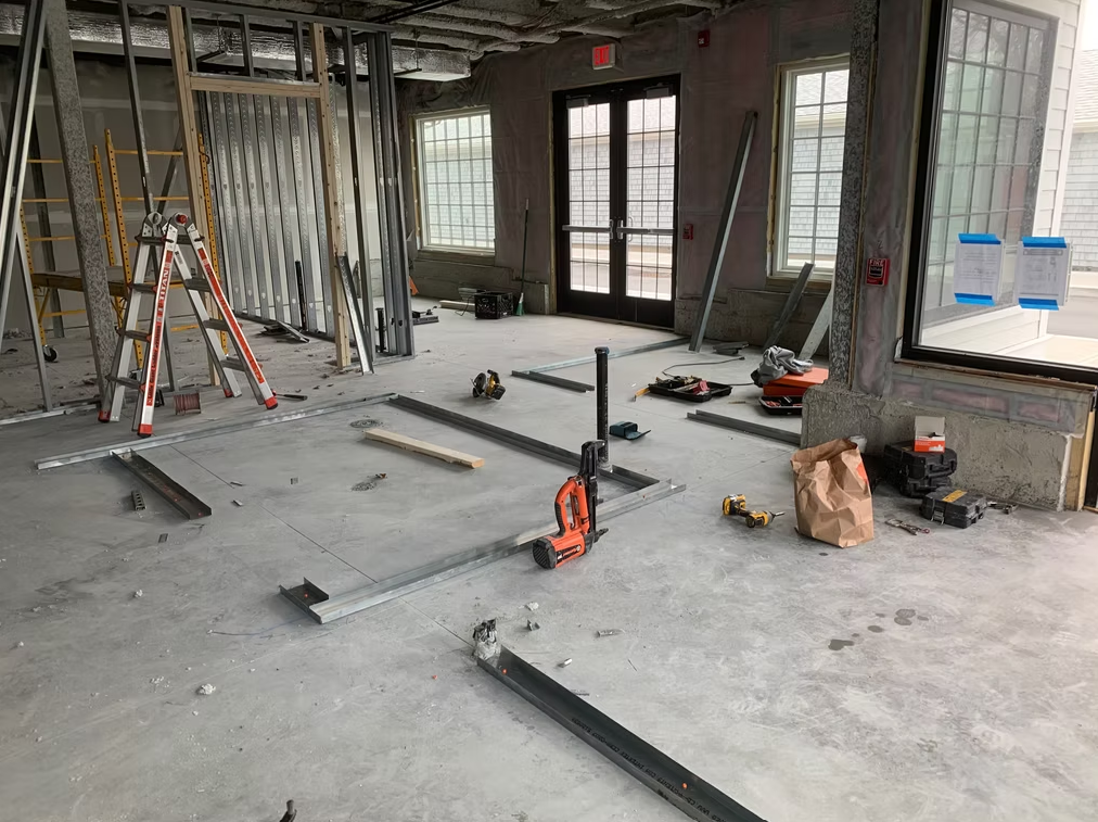 Unfinished room with tools, ladders, and metal framing on the floor during renovation.