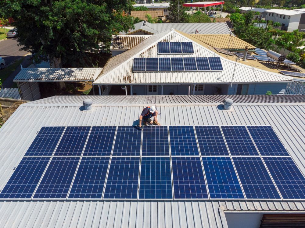 Solar Panels On A Residential Roof With A Person Working On Them — GSA Group In Garbutt, QLD