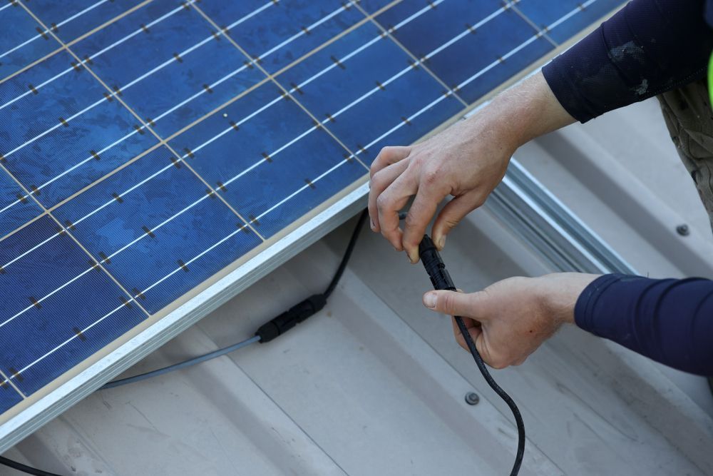 Person Connecting Electrical Wires To A Solar Panel On A Roof — GSA Group In Garbutt, QLD