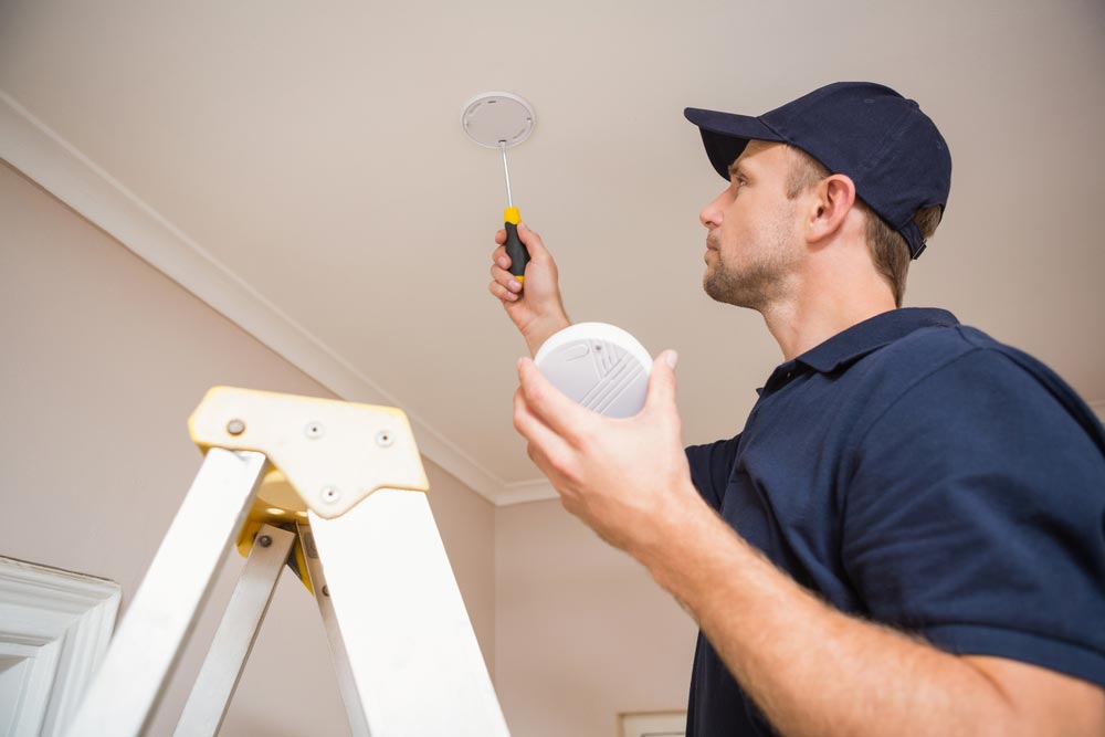 Electrician Installing Smoke Detector — GSA Group In Garbutt, QLD
