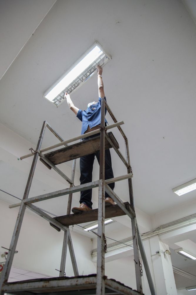 A Man is Standing on a Scaffolding Working on a Light Fixture — GSA Group In Cairns, QLD