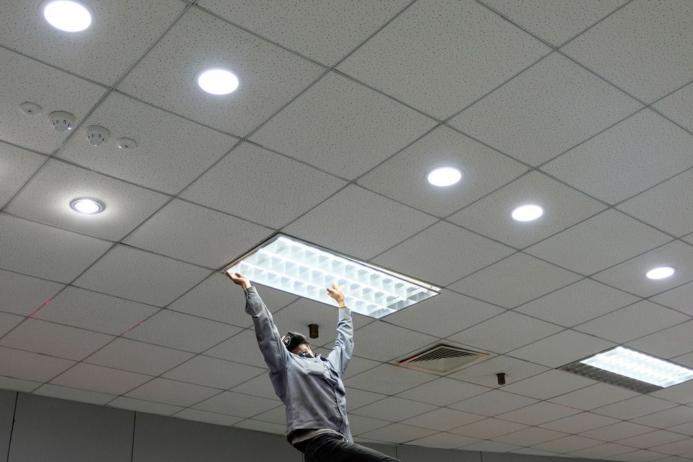 A Man is Hanging a Light Fixture From the Ceiling — GSA Group In Cairns, QLD