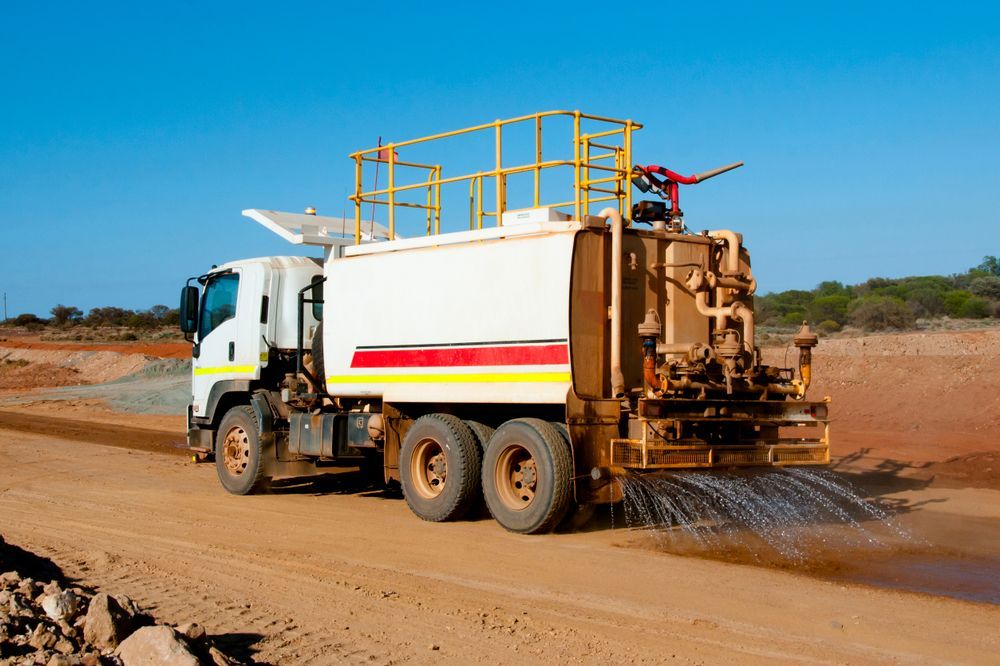 Water Truck Sprays Water on a Dirt Road, Reducing Dust During the Day— Mareeba Crane Hire In Mareeba, QLD