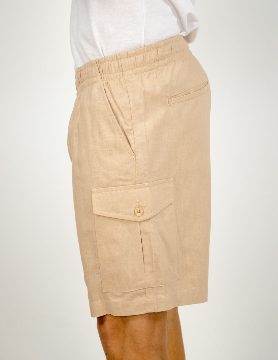 Falda cargo beige hasta la rodilla con bolsillos laterales, mostrada en una persona de pie sobre un fondo blanco.