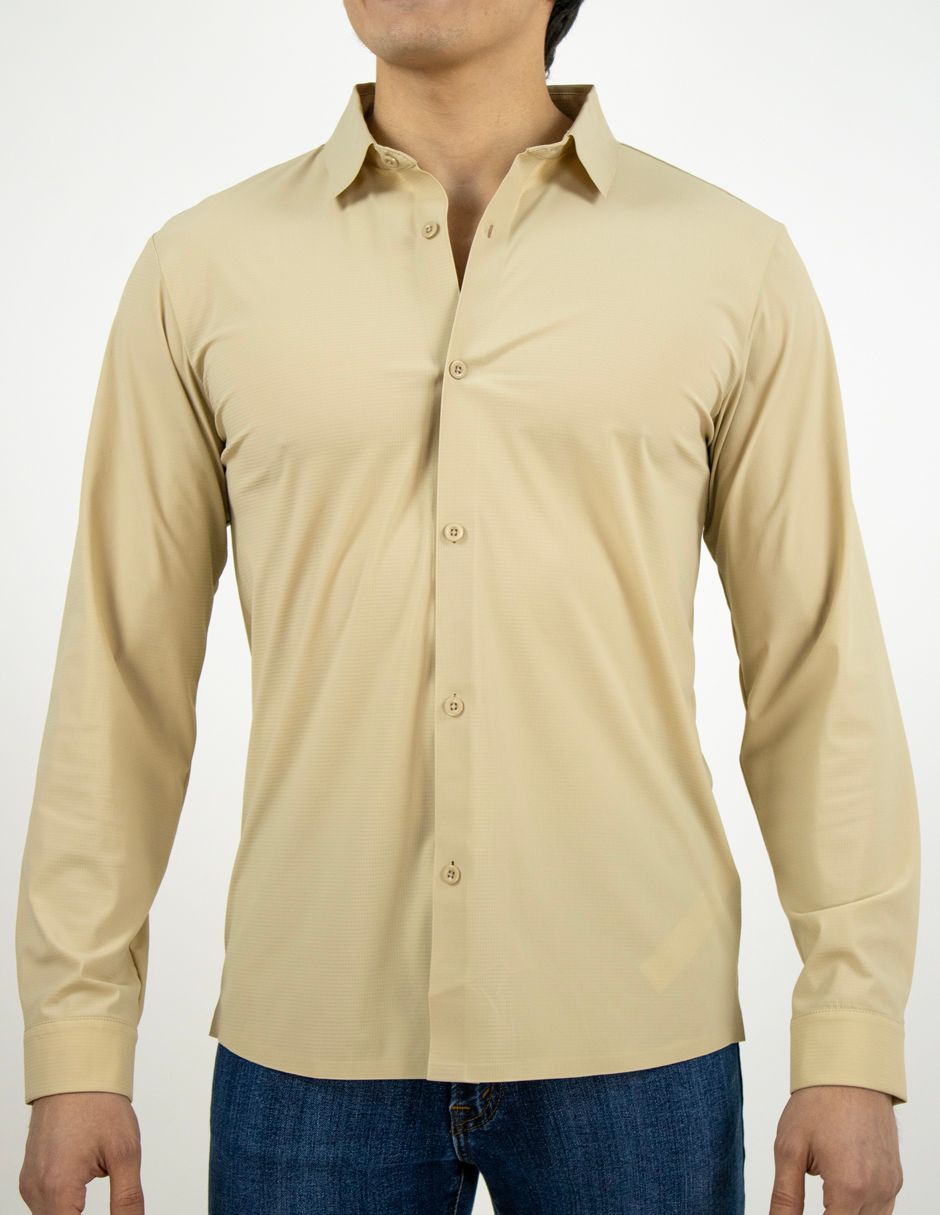 Camisa beige de manga larga abotonada usada con vaqueros azules, vista frontal sobre un fondo liso.