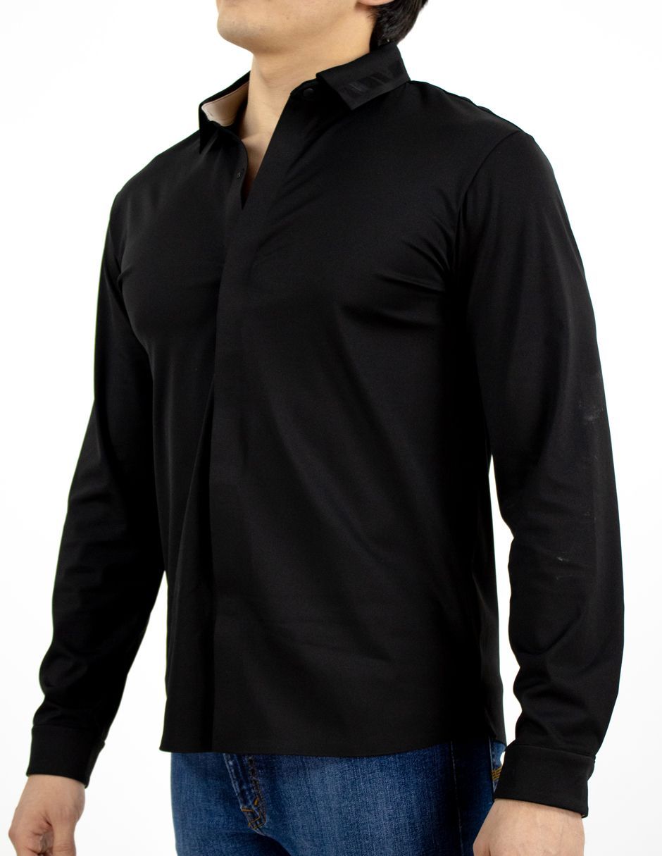 Camisa negra de manga larga con cuello, usada con jeans azules sobre un fondo blanco.
