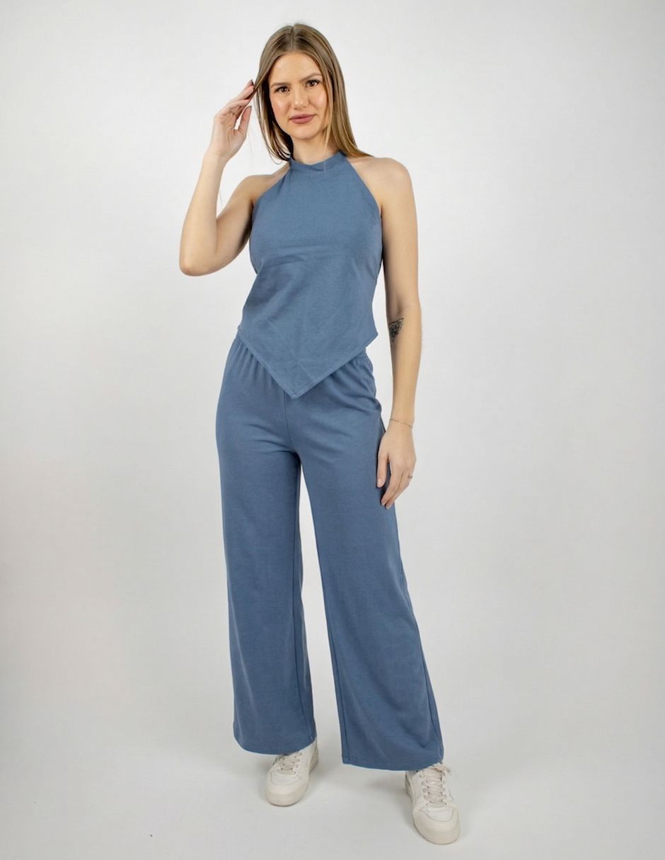 Modelo con top azul tipo halter y pantalones de pierna ancha de pie sobre un fondo blanco.