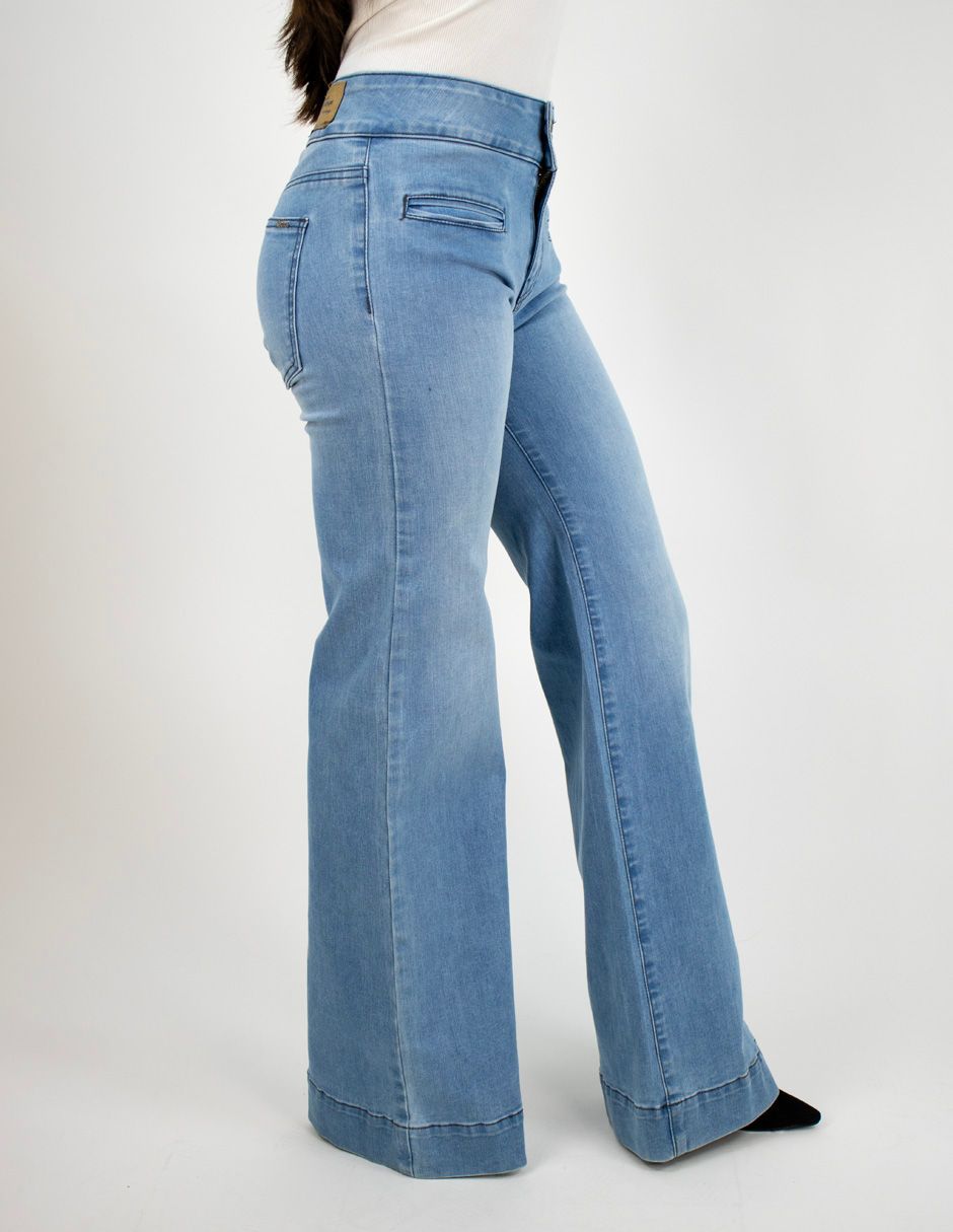 Vista lateral de unos pantalones vaqueros acampanados de color azul claro en una persona sobre un fondo blanco.