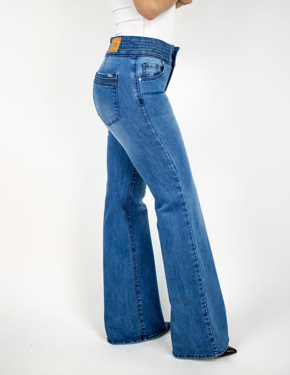 Modelo con pantalones vaqueros acampanados azules sobre un fondo blanco.
