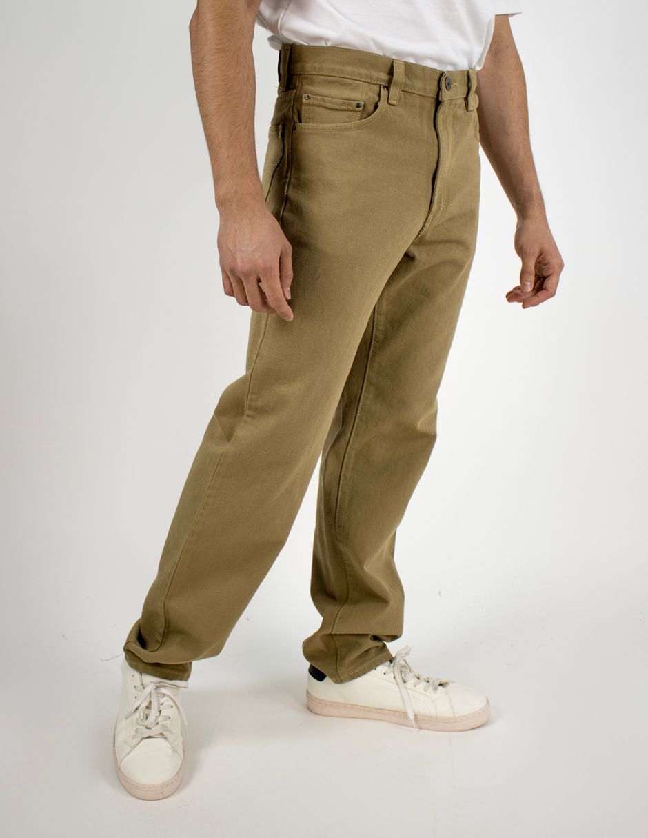 Persona vestida con pantalones caqui y zapatillas blancas de pie sobre un fondo blanco liso.