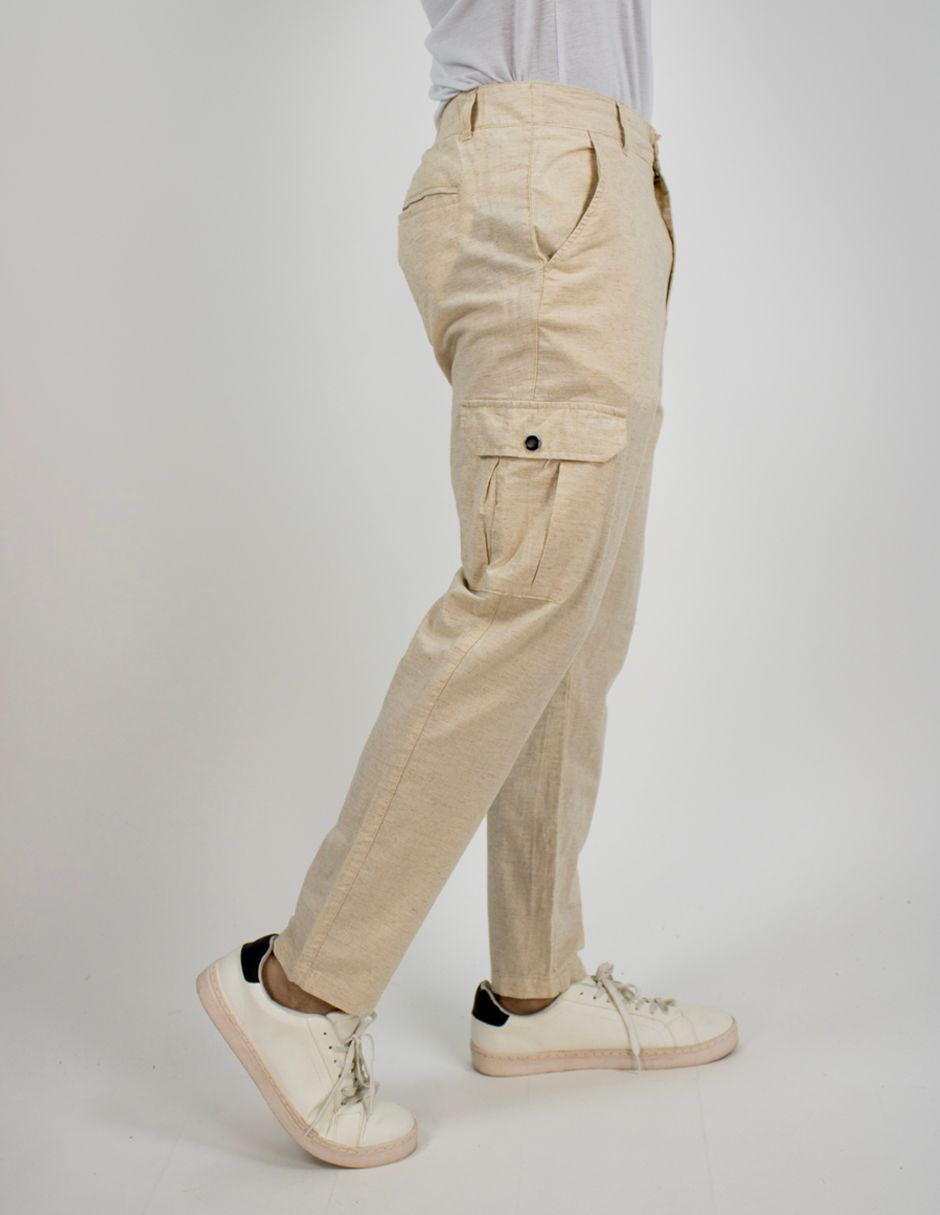 Pantalones cargo beige con dobladillos doblados y zapatillas blancas, mostrados de perfil sobre un fondo liso.