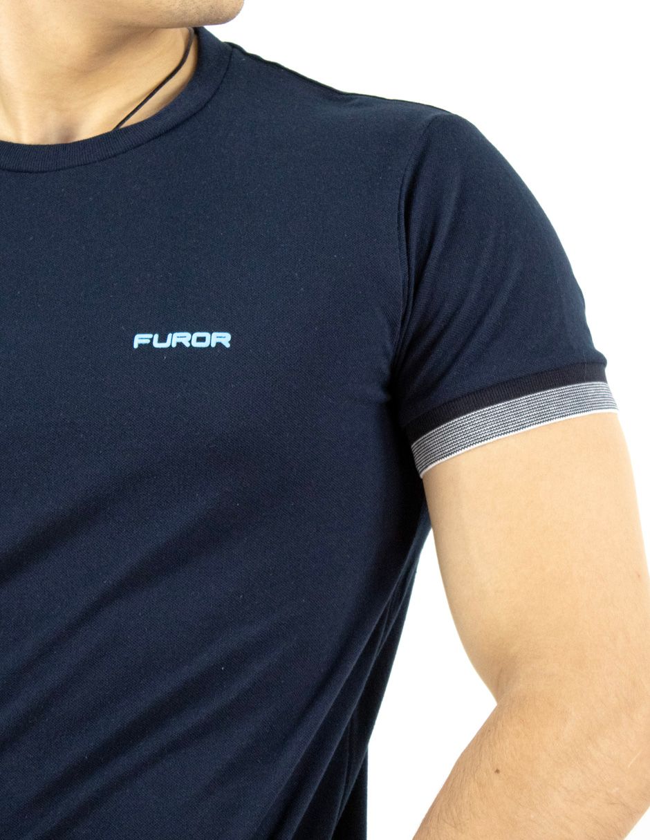 Camiseta azul marino con logo azul claro y puño de manga a rayas grises en la parte superior del torso y el brazo de una persona.