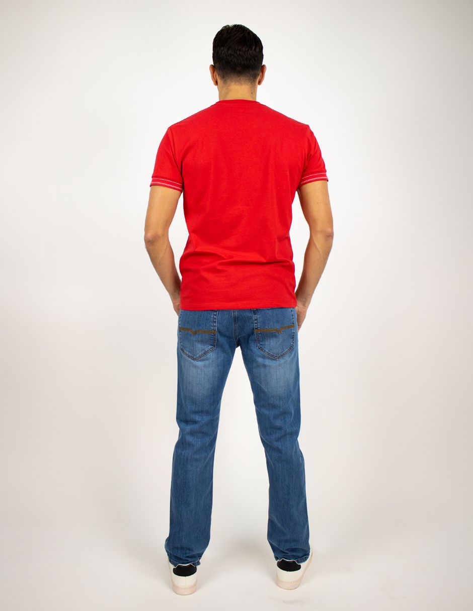 Hombre de pie de espaldas a la cámara, con camiseta roja y vaqueros, sobre un fondo blanco liso.