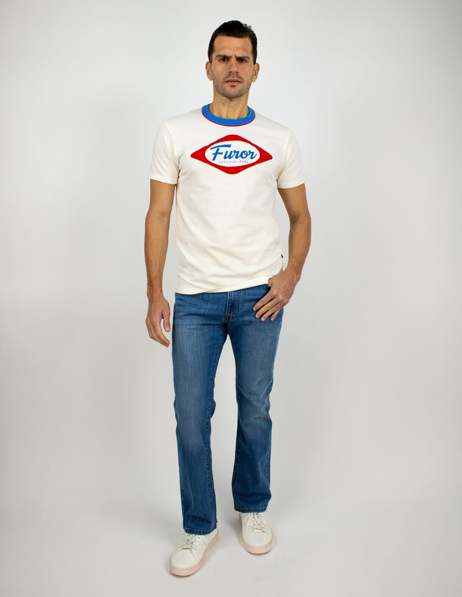 Hombre de pie sobre un fondo blanco liso, vistiendo una camiseta blanca, vaqueros azules y zapatillas blancas.