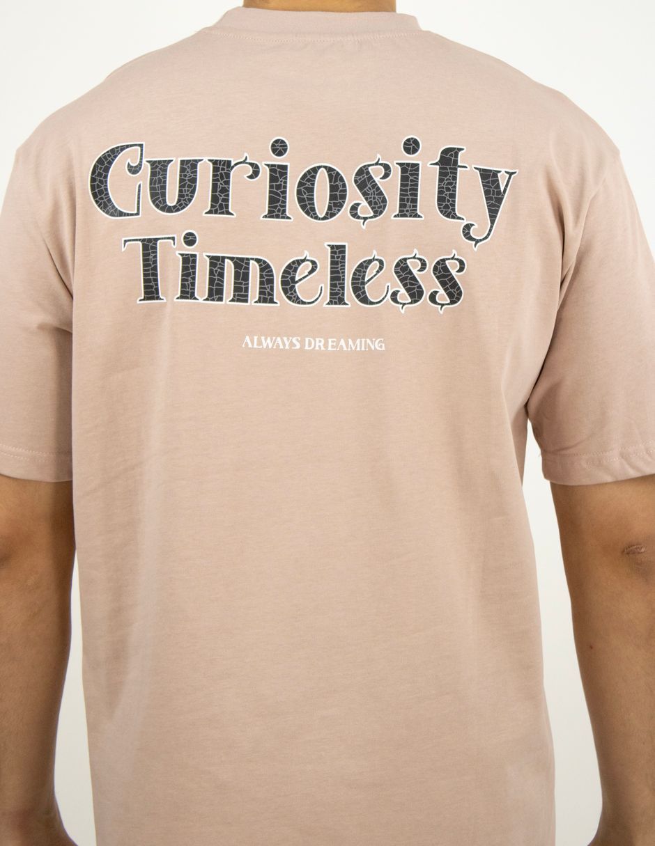 Camiseta beige con la parte trasera estampada con el texto “Curiosity Timeless” en blanco y negro.