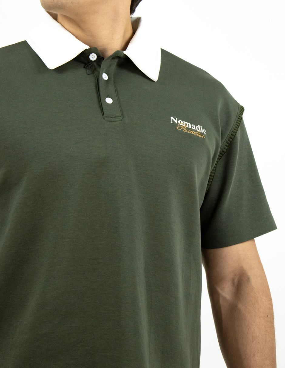 Hombre con una camisa polo verde oscuro con un pequeño logotipo en el pecho, sobre un fondo blanco.