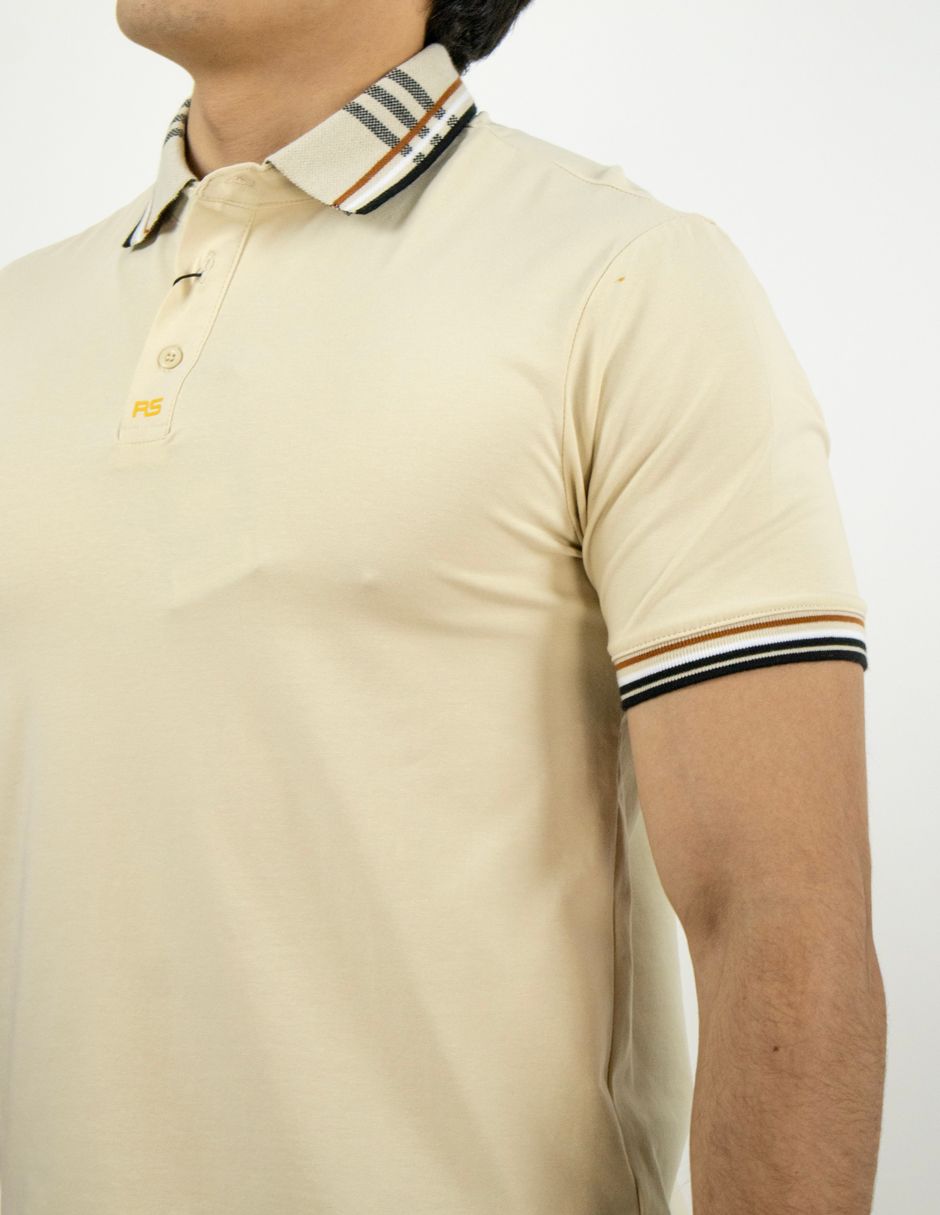 Hombre con una camisa polo beige con cuello y ribetes de las mangas a rayas, mostrado desde el pecho hacia arriba.