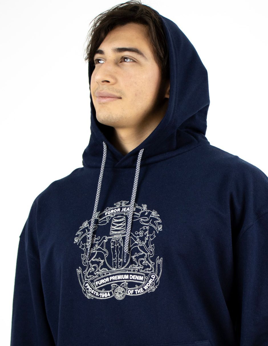 Persona con una sudadera azul marino con un gráfico blanco, mirando hacia arriba contra un fondo blanco.