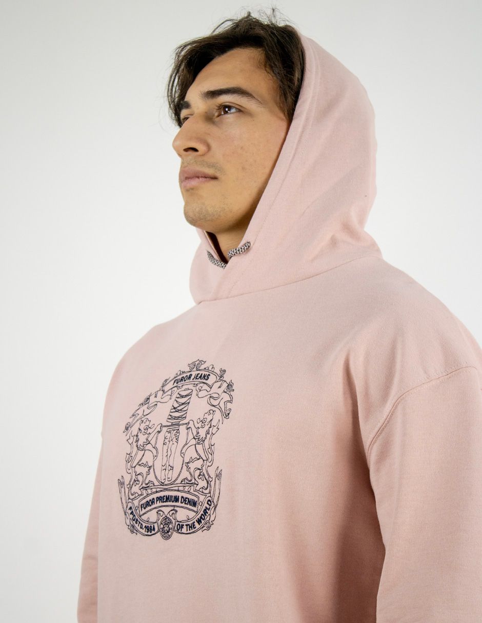 Persona con una sudadera rosa claro con un gráfico en el pecho, mostrada de perfil sobre un fondo liso.