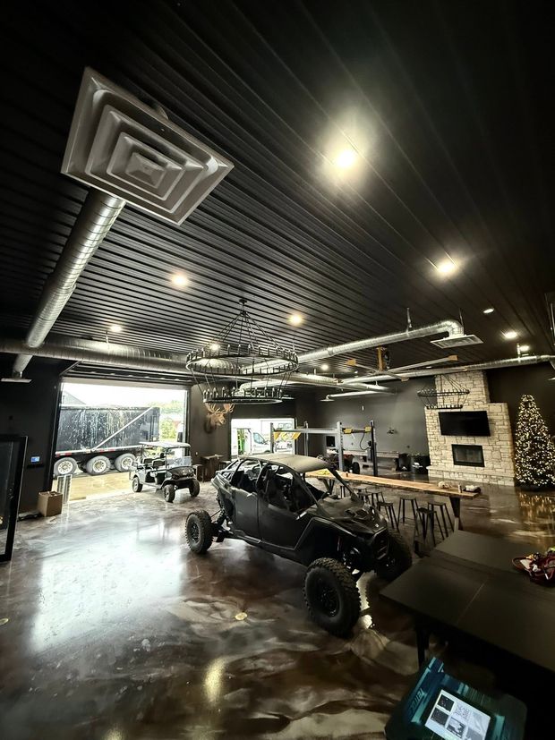 Auto workshop with a black off-road buggy under a black-and-white patterned ceiling and bright lights