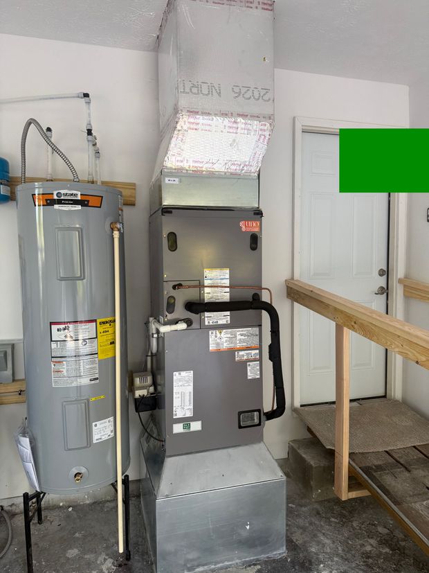 Indoor utility room with two gray HVAC units, ductwork, and a wooden railing on the right.